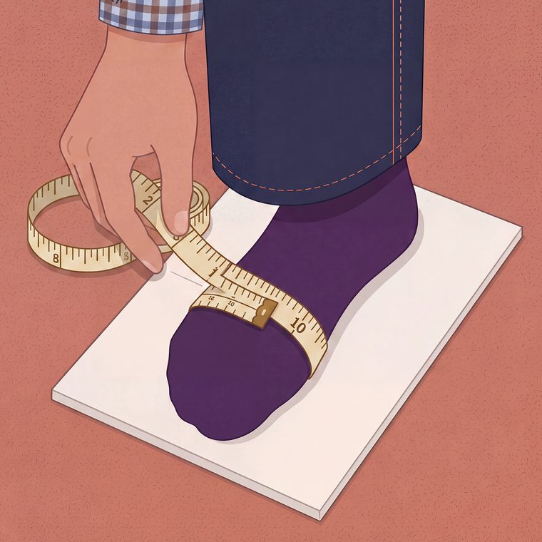 A measuring tape wrapped around the widest part of a foot in socks.